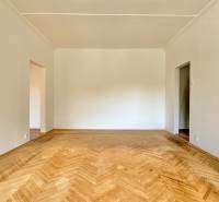 Ein geräumiges Zimmer in einer 3-Zimmer-Wohnung mit Holzboden und weißen Wänden.