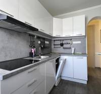 Eine Küche mit weißen Schränken, grauer Arbeitsplatte, eingebauten Geräten in einer 2-Zimmer-Wohnung.