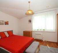Schlafzimmer im Einfamilienhaus mit Ehebett, Holzmöbeln und roten Accessoires.