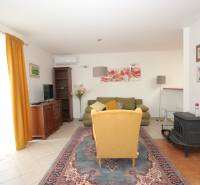 Wohnzimmer mit Blumenbildern, gelbem Sessel und grünem Sofa in einem Einfamilienhaus.
