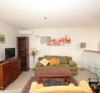 Wohnzimmer eines Einfamilienhauses mit Sofa, Sessel, Schrank und Fernseher.