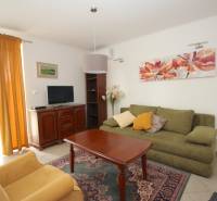 Wohnzimmer in einem Einfamilienhaus mit Sofa, Sessel, Tisch und Fernseher.