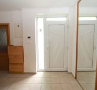 Eingangsbereich eines Einfamilienhauses mit weißen Türen, einem Spiegel und einem Holzschuhschrank.