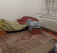 Ein Zimmer in einem Einfamilienhaus mit einem Bett, einem Teppich und Spitzenvorhängen.