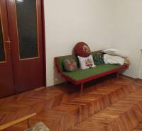 Innenraum eines Einfamilienhauses mit Holzboden, Sofa und Kissen in der Zimmerecke.