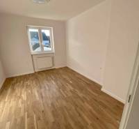 Ein Zimmer in einer 3-Zimmer-Wohnung mit Holzboden und weißen Wänden, ein Fenster mit Aussicht.