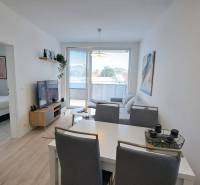 Helles Wohnzimmer mit weißen Möbeln und Zugang zum Schlafzimmer in einer Zweizimmerwohnung.