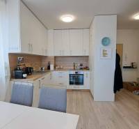 Küche in einer 2-Zimmer-Wohnung mit weißer Küchenzeile, Esstisch und Holzboden.