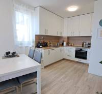 Küche in einer 2-Zimmer-Wohnung mit weißer Küchenzeile, Esstisch und Holzboden.