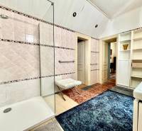 Badezimmer in einer 2-Zimmer-Wohnung mit Duschkabine, Teppich und Regalen zur Aufbewahrung.