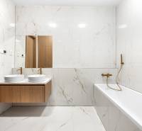 Badezimmer mit Spiegel, Doppelwaschbecken und Badewanne in einer 3-Zimmer-Wohnung.