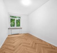 Ein Zimmer in einer 3-Zimmer-Wohnung mit Parkettboden und großem Fenster, helle Dekoration.