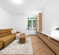 Wohnzimmer in einer 3-Zimmer-Wohnung mit braunem Sofa, Tisch und großem Fenster.