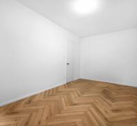 Ein leeres Zimmer in einer 3-Zimmer-Wohnung mit Fischgrätparkettboden.