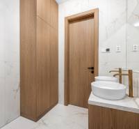 Ein Badezimmer mit zwei Waschbecken, Holzschränken und Marmorfliesen in einer 3-Zimmer-Wohnung.