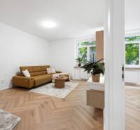 Wohnzimmer in einer 3-Zimmer-Wohnung mit braunem Sofa und Holzboden.