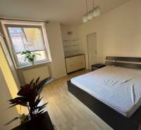 Helles Schlafzimmer mit großem Fenster und Doppelbett in einer 2-Zimmer-Wohnung.