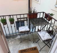Balkon einer 2-Zimmer-Wohnung mit Metallmöbeln und Blumentöpfen.