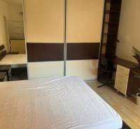Schlafzimmer in einer 2-Zimmer-Wohnung mit Bett, Schreibtisch und Kleiderschrank.