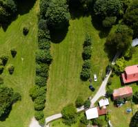 Luftaufnahme von Erholungsgrundstücken in Oščadnica mit Grünflächen, Gebäuden und einer Straße.