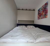 Schlafzimmer in einer 2-Zimmer-Wohnung mit Bett und farbigem Wandgemälde.