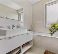 Badezimmer mit Waschbecken und Badewanne in einer 4-Zimmer-Wohnung, mit Fenster und Pflanze.
