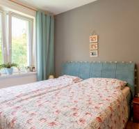 Schlafzimmer mit Bett, Vorhang in einer 3-Zimmer-Wohnung und einem Nachttisch aus Holz.