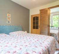 Schlafzimmer in einer 3-Zimmer-Wohnung mit blauer Kopfleuchte, Holzschrank und Dekorationen.