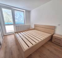 Helles Schlafzimmer mit Holzbett und Nachttischen in einer 2-Zimmer-Wohnung.