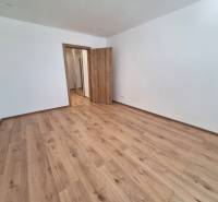 Ein leerer Raum mit Holzboden und geschlossenen Türen in einer Zweizimmerwohnung.