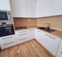 Küche in einer 2-Zimmer-Wohnung mit Holzboden und eingebauten Geräten.