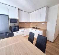 Küche in einer 2-Zimmer-Wohnung mit modernen Möbeln, Geräten und einem Esstisch.