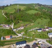 Luftaufnahme von Wohnbaugrundstücken in Raková, umgeben von grünen Hügeln und Häusern.