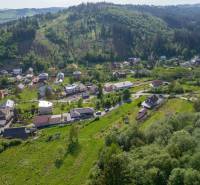 Luftaufnahme von Wohngebieten in Rakov umgeben von Grünflächen und Hügeln.