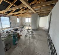 Bau in einem Einfamilienhaus mit freiliegenden Trägern und Baumaterial auf dem Boden.