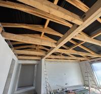 Das Einfamilienhaus hat weißen Putz, Holzbalken und eine unvollendete Decke.