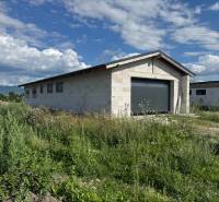 Unvollendetes Einfamilienhaus in Valča, umgeben von üppiger Vegetation und Bergkulisse.