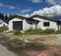 Unvollendetes Einfamilienhaus in Valča mit Garage, umgeben von Natur und Baumaterialien.
