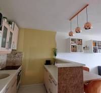 Küche in einer 2-Zimmer-Wohnung mit hängenden Leuchten und einem Holztisch.