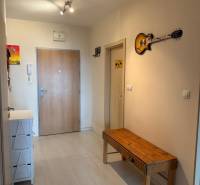 Eingangsflur in einer Zweizimmerwohnung mit einer Holzbank und einer dekorativen Gitarre an der Wand.