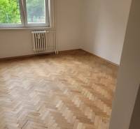 Ein Zimmer in einer 3-Zimmer-Wohnung mit Holzböden, großes Fenster, Heizkörper darunter.