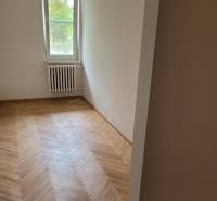Ein Zimmer in einer 3-Zimmer-Wohnung mit Holzboden und einem Heizkörper unter dem Fenster.