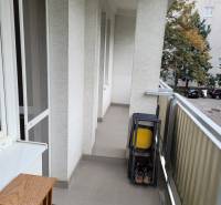 Ein Balkon in einer 3-Zimmer-Wohnung mit Klappstühlen und Blick auf die Bäume im Hof.