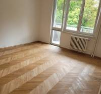 Ein Zimmer in einer 3-Zimmer-Wohnung mit Holzboden und Balkontüren.