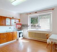 Küche in einem Einfamilienhaus mit einer Holzzeile, einem Tisch und einem großen Fenster bei der Heizung.