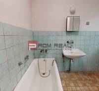 Ein Badezimmer in einem Einfamilienhaus mit Badewanne, Waschbecken und älteren Fliesen.