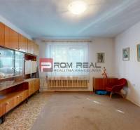 Wohnzimmer eines Einfamilienhauses mit Möbeln, großem Fenster und Vorhängen.