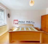Ein Schlafzimmer in einem Einfamilienhaus mit Holzboden, einem Bett und einem Fenster mit Blick auf den Garten.
