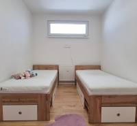 Einfaches Zimmer mit zwei Betten und Spielzeug in einer 4-Zimmer-Wohnung.