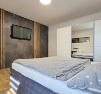 Schlafzimmer in einer 4-Zimmer-Wohnung mit einem bequemen Bett, einem Kleiderschrank und einem Fernseher.